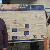 Sal Alaimo and Bex Takacs-Britz standing in front of their poster